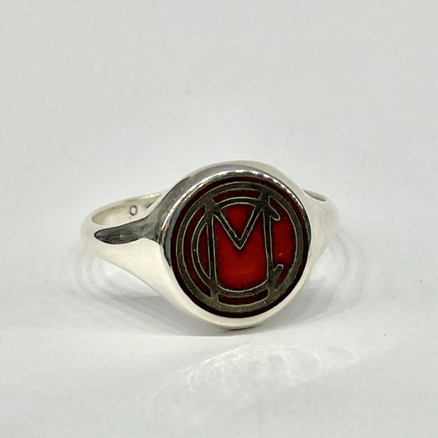 Front view of the Mori Calliope MC emblem ring in sterling silver, filled with red vitreous enamel
