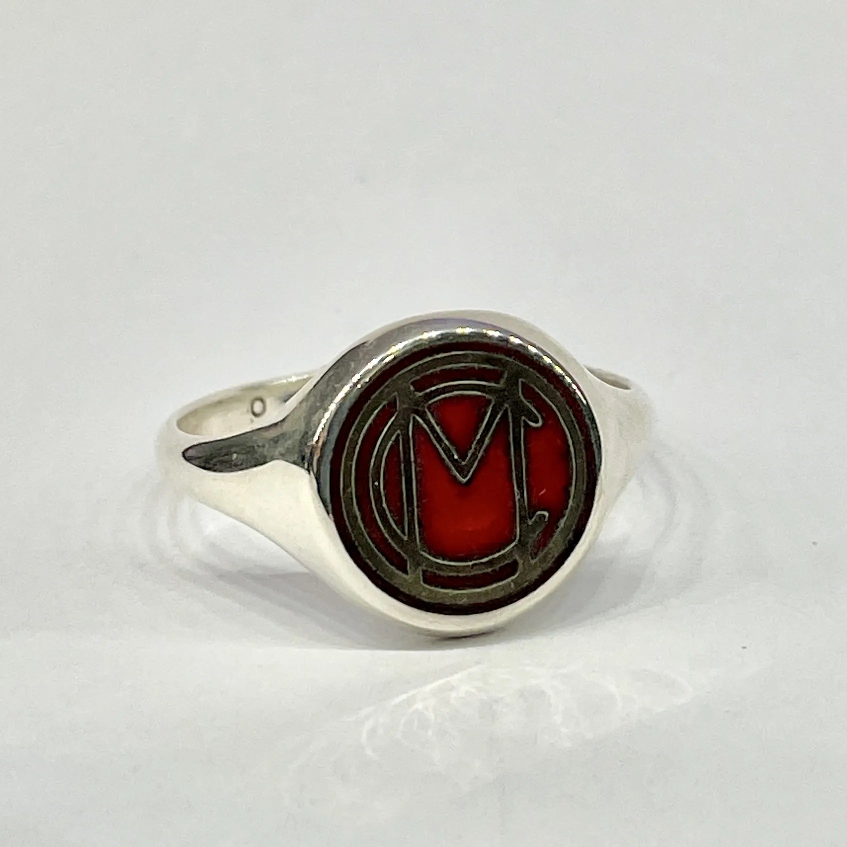Front view of the Mori Calliope MC emblem ring in sterling silver, filled with red vitreous enamel