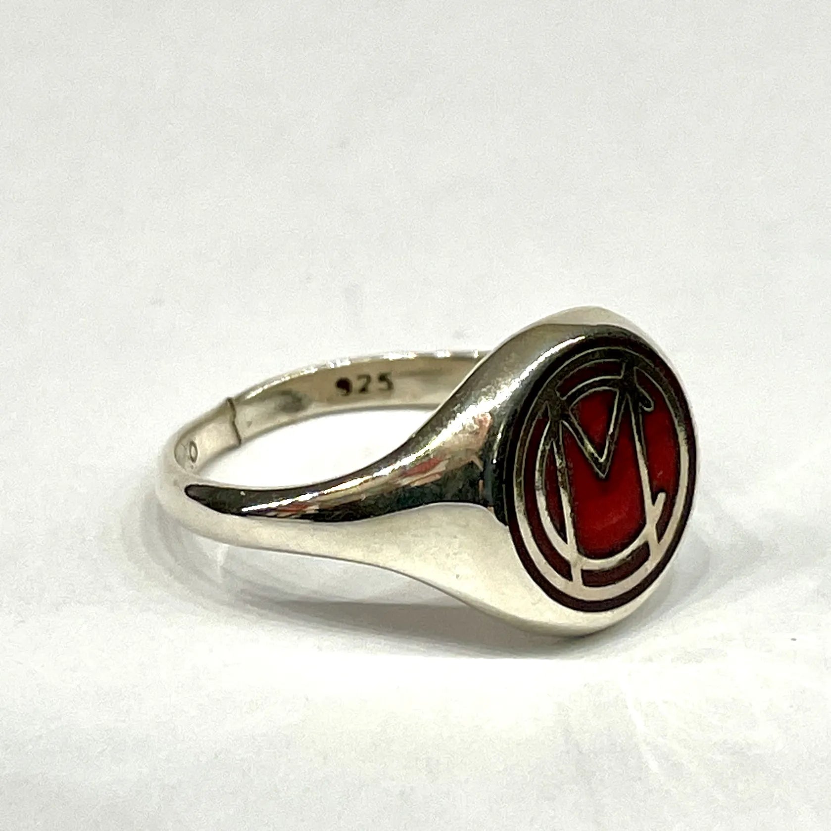 Angled side profile of the sterling silver Mori Calliope ring, showing the red enamel MC emblem.