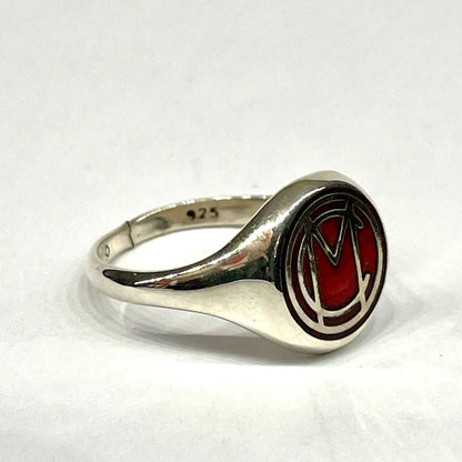 Angled side profile of the sterling silver Mori Calliope ring, showing the red enamel MC emblem.